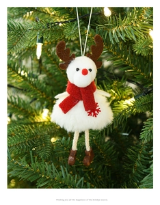 Close-up of a plush reindeer ornament hanging on a Christmas tree with warm lights