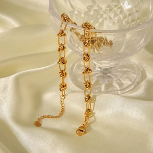 Detail of 18K gold stainless steel knotted paperclip chain on champagne silk