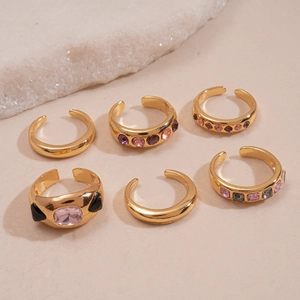 6-piece gold geometric ring set with colorful crystals on a natural stone background