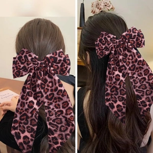 Detailed view of pink leopard print bow hair clip with double long ribbons on hair
