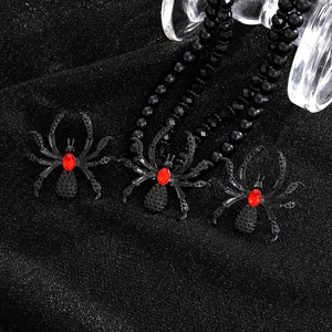 Macro shot of black spider jewelry set with red stones and beaded necklace details
