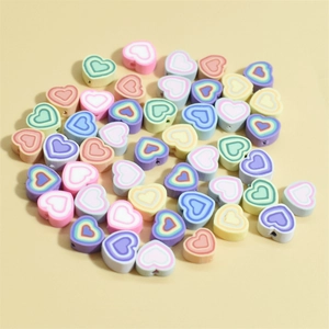 Perles en forme de cœur de 10mm colorées pour bracelets DIY sur fond jaune vif
