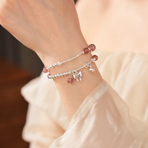 Dettaglio del bracciale di perle di quarzo fragola con fiocco argento e ciondoli a campanello