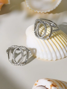 Macro detail of silver double oval rings with cubic zirconia on a white shell