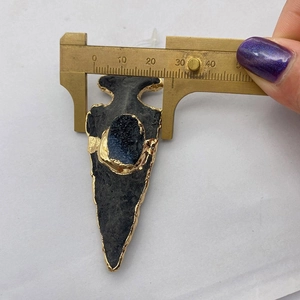 Close-up of measuring the width of the black stone cone pendant with a brass caliper
