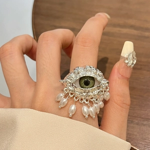 Detailed view of evil eye ring with silver texture, green iris, and hanging pearls