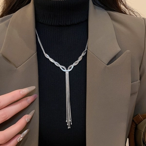 Detail of a silver layered fringe necklace styled on a model with a blazer and sweater