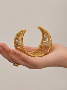Détail d'un large bracelet doré avec un tissage complexe de fils métalliques entrelacés