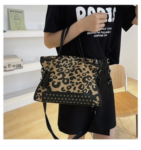 Detail of leopard print tote bag featuring black tassel charm and metal base studs