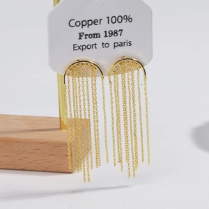 Detailed close-up of 18K gold-plated crescent moon earrings with long dangling tassels