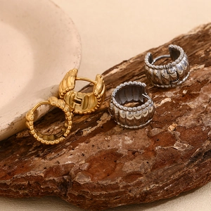 Detail of vintage twist earrings in gold and silver finish on textured rustic background