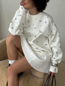 Detailed close-up of crewneck sweatshirt with blue floral print and elastic cuffs