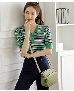 Detail showing light green quilted crossbody bag with adjustable strap on a female model
