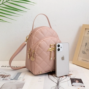 Pink quilted mini backpack with gold flamingo charm shown next to a smartphone for size scale