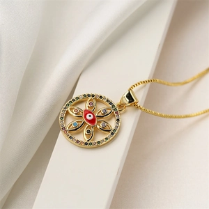 Macro detail of gold evil eye pendant with red enamel and colorful zircon stones