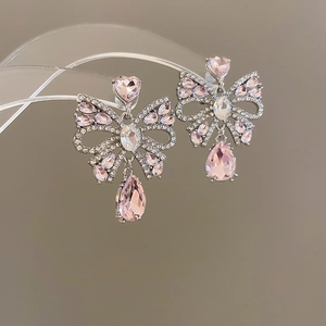 Detail of pink crystal bow earrings with silver drop tassels and heart-shaped studs
