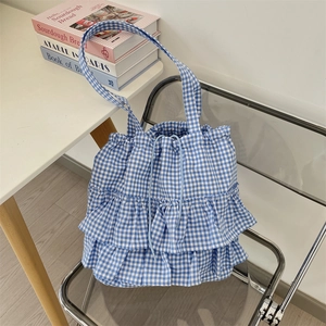 Detailed close-up of blue and white gingham tote bag with layered ruffle trim on a chair