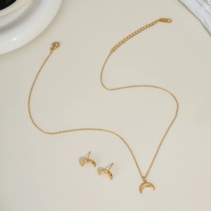 Macro shot of gold moon-shaped jewelry set featuring zircon-encrusted necklace and earrings