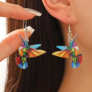 Primer plano de pendientes de colibrí en acrílico colorido con ganchos plateados elegantes