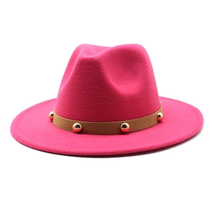Detail of rose red fedora hat with a light brown suede band featuring golden metal studs