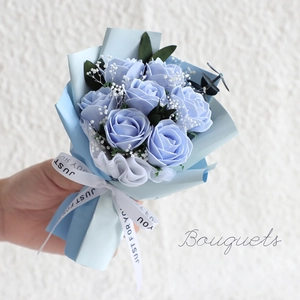 Handheld bouquet of blue soap roses with gypsophila in light blue matte gift wrap