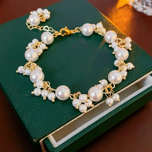 Detailed view of the white pearls and gold chain on a green textured jewelry box