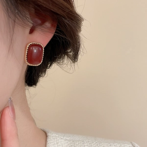 Detailed close-up of a vintage red oval earring with a twisted gold edge decoration
