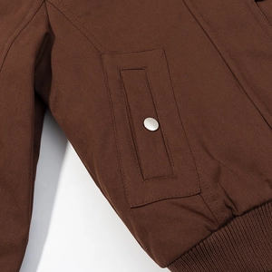 Detailed macro view of brown twill cotton fabric with silver snap button and ribbed cuff
