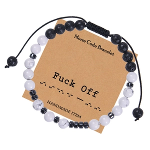Detail of Morse code bracelet with black lava and white stones on themed display card