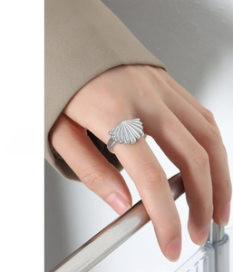 Detailed close-up of a silver stainless steel scallop shell ring on a female finger