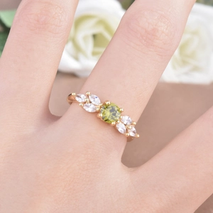 Detailed view of an olive green zircon ring with gold leaf design on white roses