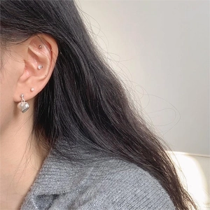 Close-up of polished 925 sterling silver heart drop earring and pearl stud styling