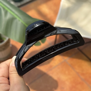 Detailed view of a 10cm black glossy butterfly hair claw clip held in hand