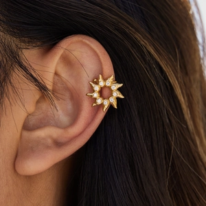 Golden sunburst stud earrings with sparkling zircon stones worn by a model