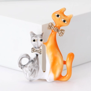 Detailed view of twin cat brooches with orange resin and marble grey enamel texture