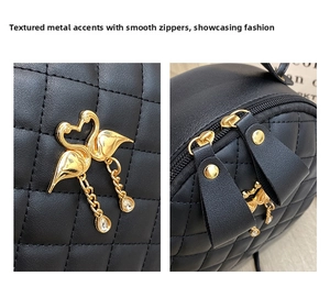 Detail of black quilted bag featuring gold swan charm with crystals and smooth metal zipper