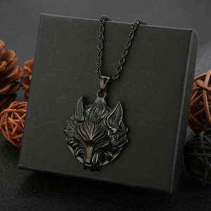 Nahaufnahme von schwarzem Wolfskopf-Anhänger aus Edelstahl mit Kordelkette und Tannenzapfen