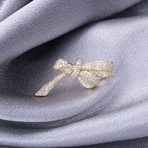 Elegant gold bow brooch with micro-set zircon crystals on grey satin fabric background