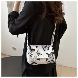 Model wearing a white crossbody square bag featuring a stylish black butterfly print