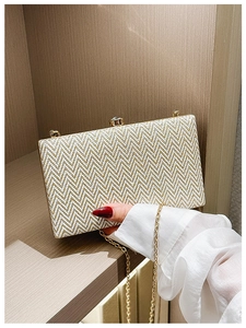 Close-up of a wavy gold and white acrylic clutch bag with a metallic chain strap