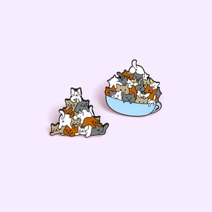 Cute enamel pins featuring colorful cartoon cats stacked and playing in a blue teacup