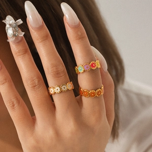 Close-up of three colorful daisy enamel open rings in gold finish worn by a model