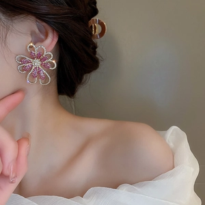 Makroaufnahme von Kristall-Blumenohrringen mit rosa-weißen Strasssteinen am Modell