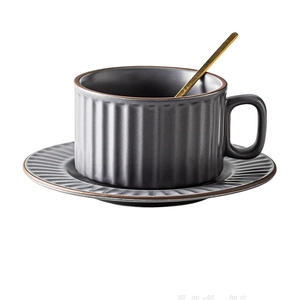 Detail view of matte grey ceramic coffee cup with vertical ribbed texture and gold spoon