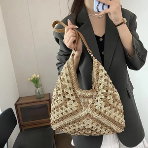 Dettaglio della borsa in paglia intrecciata beige con tracolla in pelle marrone
