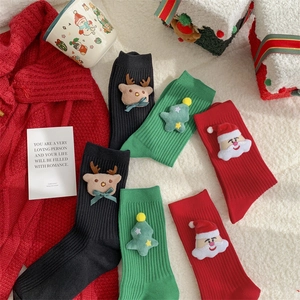 Close-up of Christmas socks with 3D reindeer and Santa plush charms on wool background