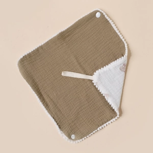 Detail of olive green cotton muslin baby bib with pom-pom trim and white snap buttons