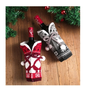 Close-up of red and grey knitted wine bottle covers with snowflake patterns and bows