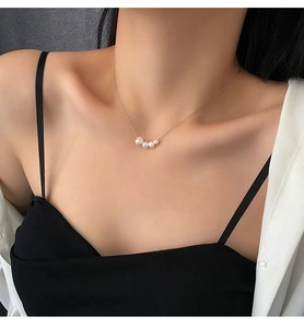 Close-up of elegant gold titanium steel necklace with four natural pearls on collarbone