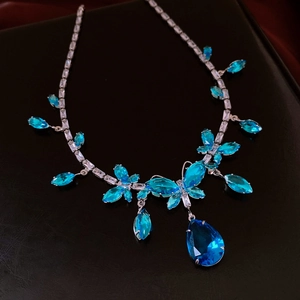 Makroansicht einer Silberhalskette mit funkelnden blauen Zirkonia im floralen Tropfendesign